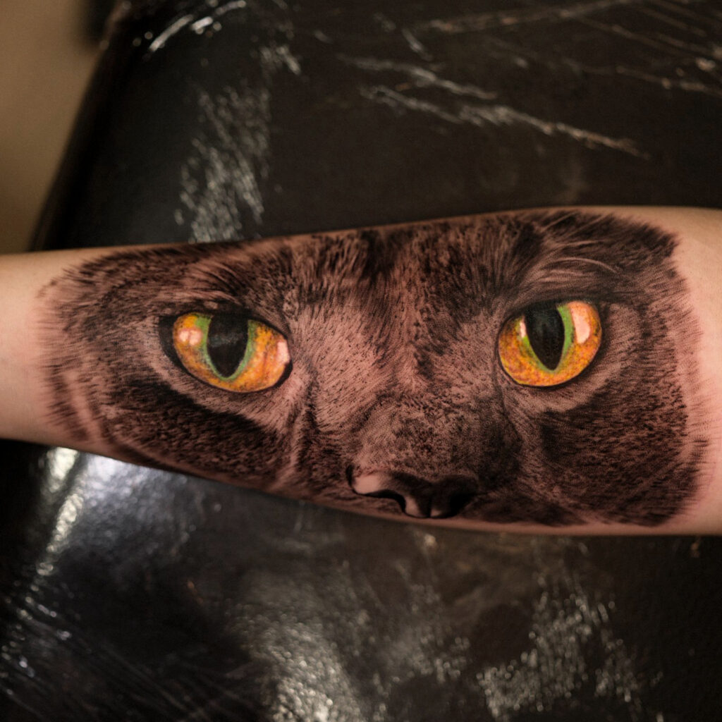 Black and grey cat eyes tattoo across forearm