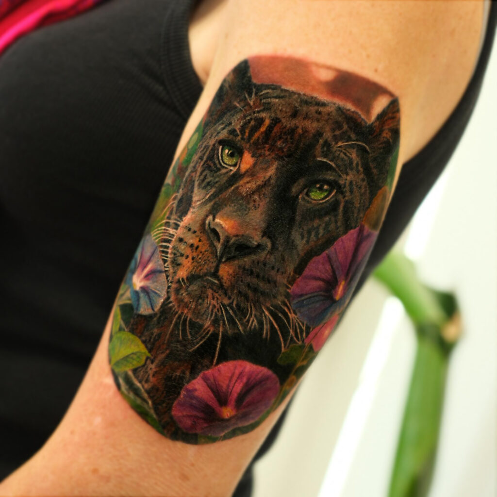 Colour realism black jaguar tattoo with flowers on upper arm