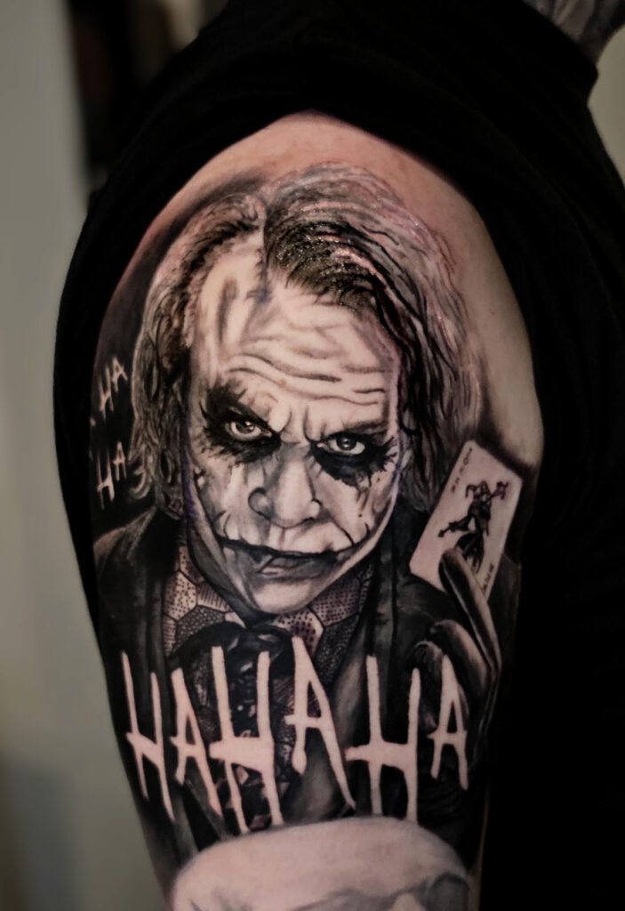 Black and grey realism Joker portrait tattoo on upper arm
