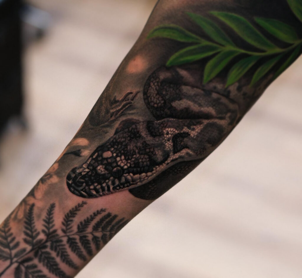 Black and grey snake tattoo detail on forearm