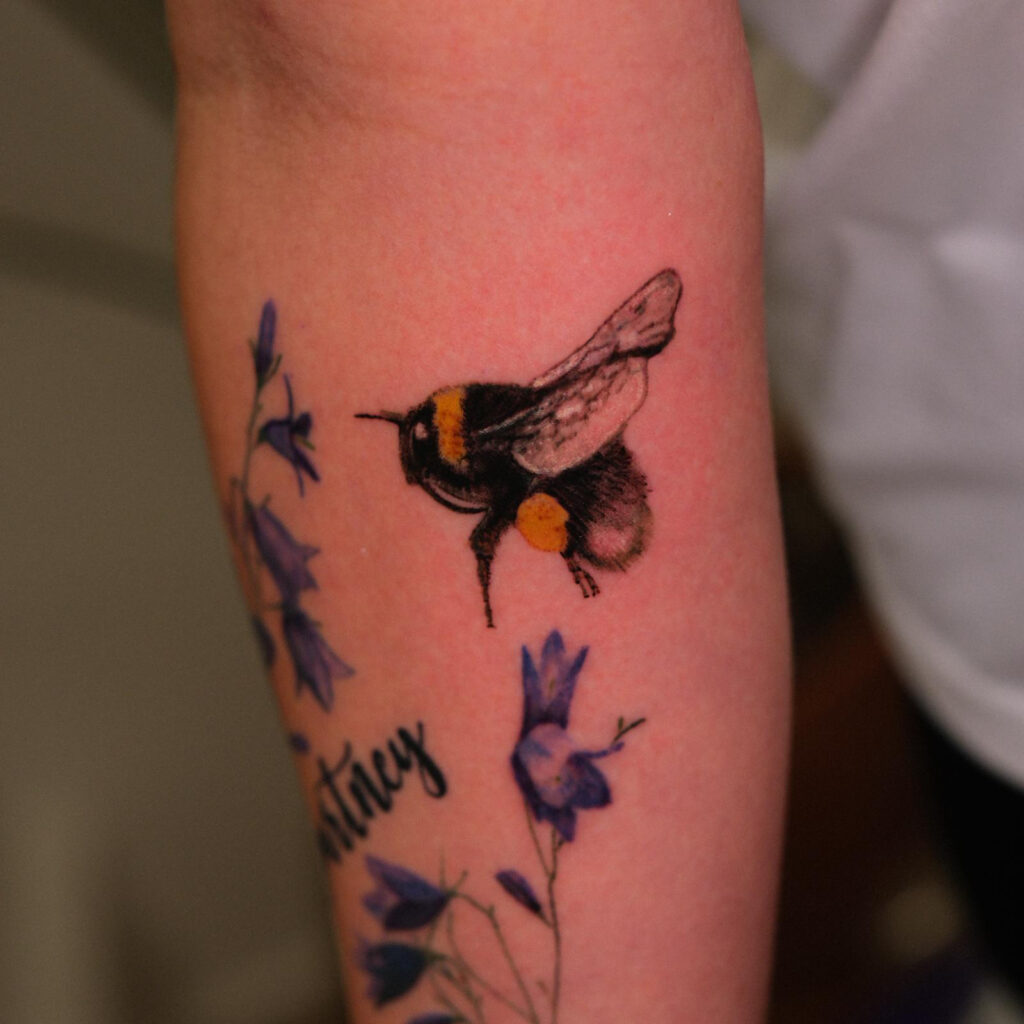 Small bumblebee tattoo with blue flowers
